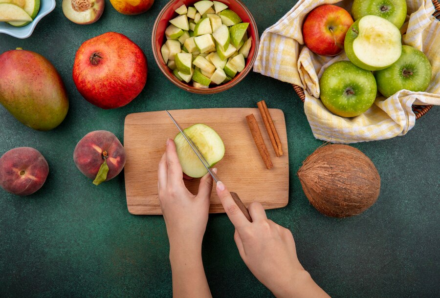 Top View Female Hands Cutting Apple Into Slices Kitchen Board With Knife With Cinnamon Sticks Coconut Peach Isolated Green 141793 17213